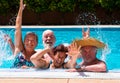 Happy group of friends playing enjoying the swimmin pool together. Bright sunlight and transparent water. Large smiles and arms Royalty Free Stock Photo