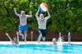 Happy group of mature people enjoying summer and swimming pool, jumping and playing with inflatable ball Royalty Free Stock Photo