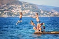 Happy group of people, children and adults, jumping in the water off dock, splashing and having fun Royalty Free Stock Photo