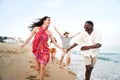 Happy group of young people having fun at the beach. Cheerful friends run holding hands enjoying the summer Royalty Free Stock Photo