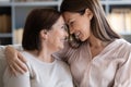 Happy grown up daughter touching foreheads with mother.