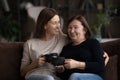 Happy grownup daughter and older middle aged mom drinking tea