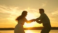 Happy guy and girl waltz in the evening in the summer park. Loving man and woman dance in bright rays of sun on the Royalty Free Stock Photo