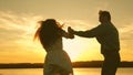 Happy guy and girl waltz in the evening in the summer park. Loving man and woman dance in bright rays of sun on the Royalty Free Stock Photo