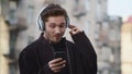 Happy guy listening music headphones outside. Smiling man dancing on city street Royalty Free Stock Photo