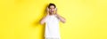 Happy guy listening music in new headphones, buying earphones on black friday, standing over yellow background Royalty Free Stock Photo