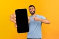Happy guy presenting smartphone with black screen, pointing at gadget Royalty Free Stock Photo