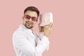 Happy man isolated on pink background shaking present and trying to guess what's inside Royalty Free Stock Photo