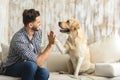 Happy guy sitting on a sofa and looking at dog Royalty Free Stock Photo