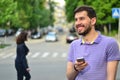 Happy guy with smartphone smiling messaging outdoors Royalty Free Stock Photo