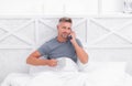 Happy guy talking on mobile phone while drinking morning tea or coffee in bed, call Royalty Free Stock Photo