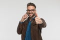Happy guy talking on the phone, smiling and making thumbs up gesture Royalty Free Stock Photo