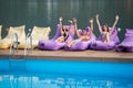 Happy guy and two attractive girls sitting on a cushioned lounger with his hands raised up and looking at the camera