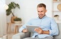 Happy guy using digital tablet sitting on the couch Royalty Free Stock Photo