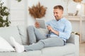 Happy guy using digital tablet sitting on sofa Royalty Free Stock Photo