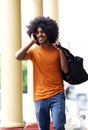 Happy guy walking in town with mobile phone and bag Royalty Free Stock Photo