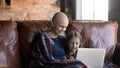 Happy hairless mother with little daughter using laptop, enjoying weekend Royalty Free Stock Photo