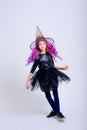 Happy Halloween. Beautiful young child girl in a witch costume , purple wig, broom on a white background. In isolation. Walpurgis Royalty Free Stock Photo