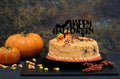 Happy Halloween cake with orange frosting, Happy Halloween banner and Halloween decorations in a Halloween setting. Low light