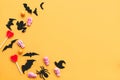 Happy Halloween.  Halloween candy border with skulls, black bats, ghost, spider paper decorations on yellow background. Copy space Royalty Free Stock Photo