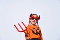 Happy Halloween. A child in a devil costume with a Trident and horns