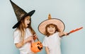 Happy Halloween. Children with a trident, a basket in the form of a pumpkin and hats on a blue background with copy