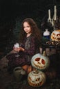 Happy Halloween Concept! Cute little witch cooking a potion in the decorated garden Royalty Free Stock Photo