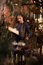 Happy Halloween Concept! Cute little witch cooking a potion in the decorated garden. Royalty Free Stock Photo