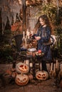 Happy Halloween Concept! Cute little witch cooking a potion in the decorated garden. Royalty Free Stock Photo