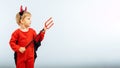 Happy Halloween! Cute little boy in devil halloween costume with horns and trident on light blue background