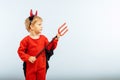 Happy Halloween! Cute little boy in devil halloween costume with horns and trident on light blue background Royalty Free Stock Photo