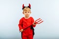 Happy Halloween! Cute little boy in devil halloween costume with horns and trident on light blue background Royalty Free Stock Photo