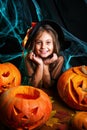 Happy halloween. Pretty little child girl in witch costume with carving pumpkin . Happy family preparing for Halloween. Royalty Free Stock Photo