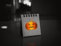 Happy Halloween day calendar with shiny pumpkin graphic icon on black folding desk calendar standing on desk.