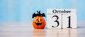 Happy Halloween day with 31 October calendar wood, jack o lantern pumpkin and bat decor with funny face on table background with