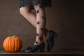 Happy halloween! Female feet in stockings with an orange pumpkin