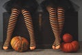 Happy halloween! Female feet in stockings with an orange pumpkin.