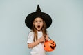 Happy Halloween. A frightened girl in a witch& x27;s hat and with a bucket in the form of a pumpkin says wow. Copy space Royalty Free Stock Photo