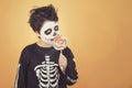 Happy Halloween.funny child in a skeleton costume eating lollipop in halloween