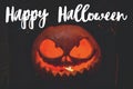 Happy Halloween greeting card. Hand written Happy Halloween text on background of spooky pumpkin Jack-o`-lantern with glowing fac Royalty Free Stock Photo