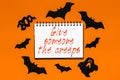 Happy halloween holiday concept. Notepad with text Give someone the creeps on white and orange background with bats, pumpkins and