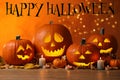 Happy Halloween. Jack o`lanterns, autumn leaves and candles on table against orange background with blurred lights Royalty Free Stock Photo