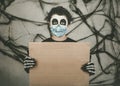Happy Halloween. kid wearing medical mask in a skeleton costume holding brown board