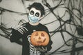 Happy Halloween.kid wearing medical mask in a skeleton costume with halloween pumpkin