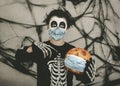 Happy Halloween,kid wearing medical mask in a skeleton costume with halloween pumpkin