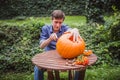 Happy halloween. Man carving big pumpkin on a wooden table for Halloween outside. Close-up Royalty Free Stock Photo