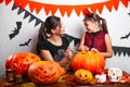 Happy Halloween. Mother and daughter carving pumpkin. Family preparing for holiday.