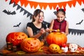 Happy Halloween. Mother and daughter carving pumpkin. Family preparing for holiday.