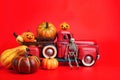 Happy Halloween, orange pumpkins in red toy truck with human skeleton on red background