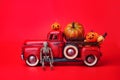 Happy Halloween, orange pumpkins in red toy truck with human skeleton on red background